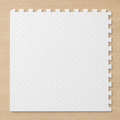 White interlocking foam puzzle mat with a diamond pattern texture, on a light wood floor.
