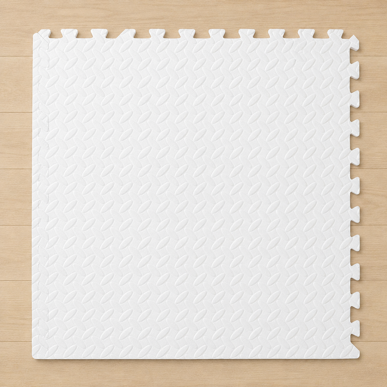 White interlocking foam puzzle mat with a diamond pattern texture, on a light wood floor.