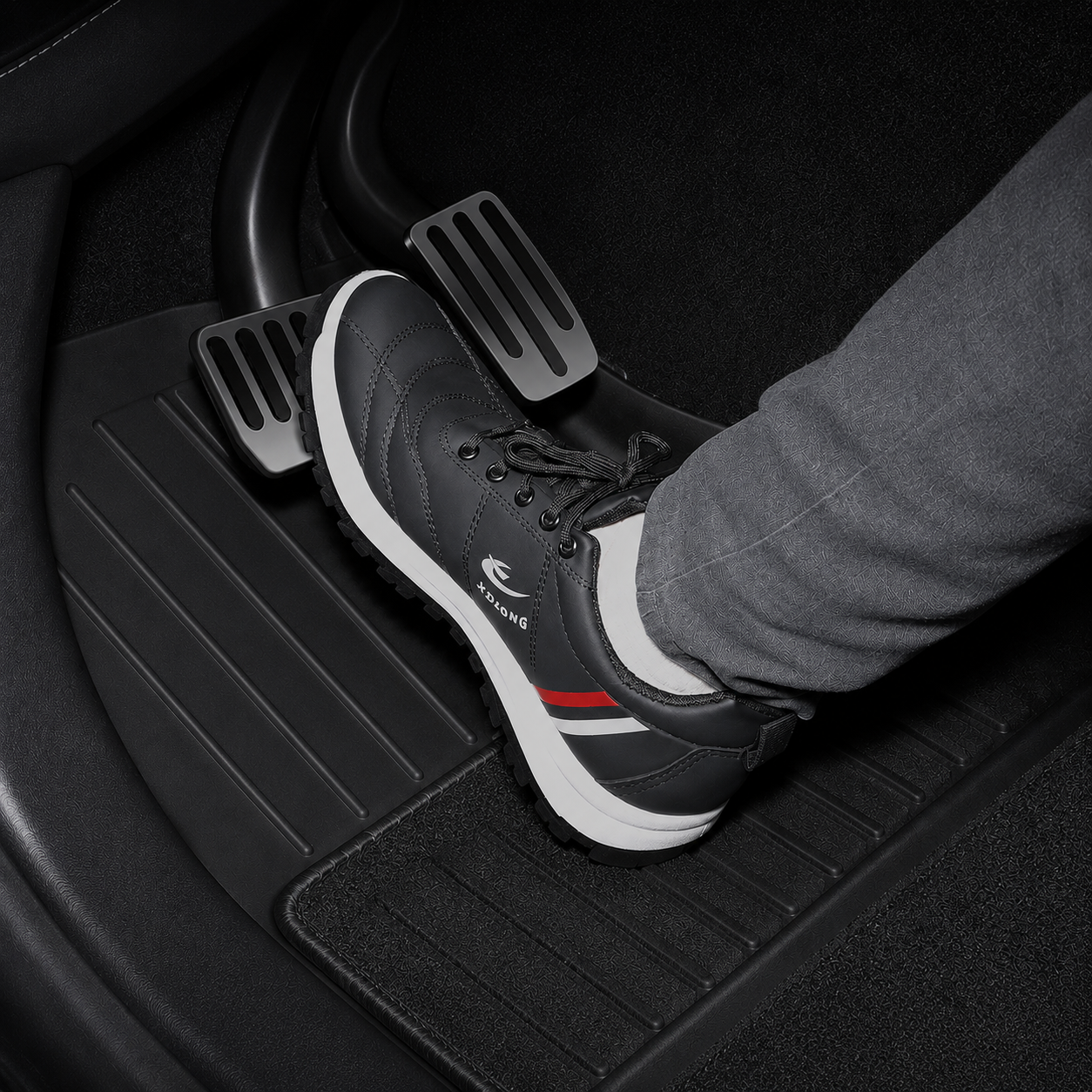 Black floor mats for a Tesla Model 3 Highland, with a person's foot on the accelerator pedal.
