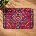 Vibrant Berber rug with a diamond pattern in pink, teal, and yellow on a wooden floor.
