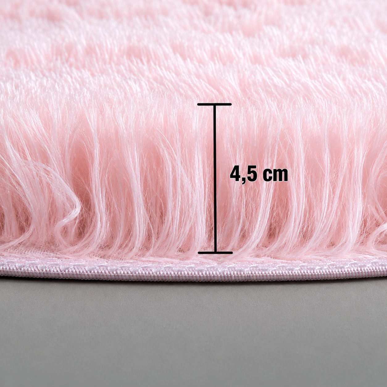 Close-up of a plush pink round rug showing a pile height of 4.5 cm.
