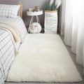 Plush white bedroom rug with a soft, shaggy texture placed on a light wood floor next to a bed.