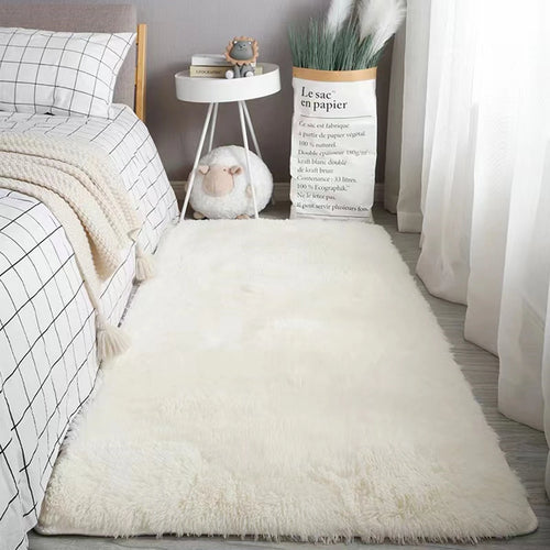 Plush white bedroom rug with a soft, shaggy texture placed on a light wood floor next to a bed.