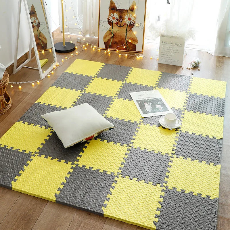 Yellow and gray interlocking foam play mat tiles arranged in a checkerboard pattern on a wooden floor.
