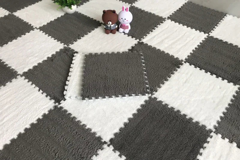 Plush interlocking floor tiles in a grey and white checkerboard pattern, with two small stuffed animals on top.