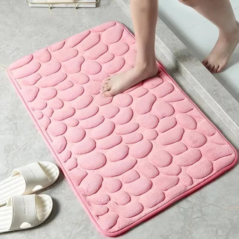 Plush pink pebble-textured bath mat with a person stepping onto it.