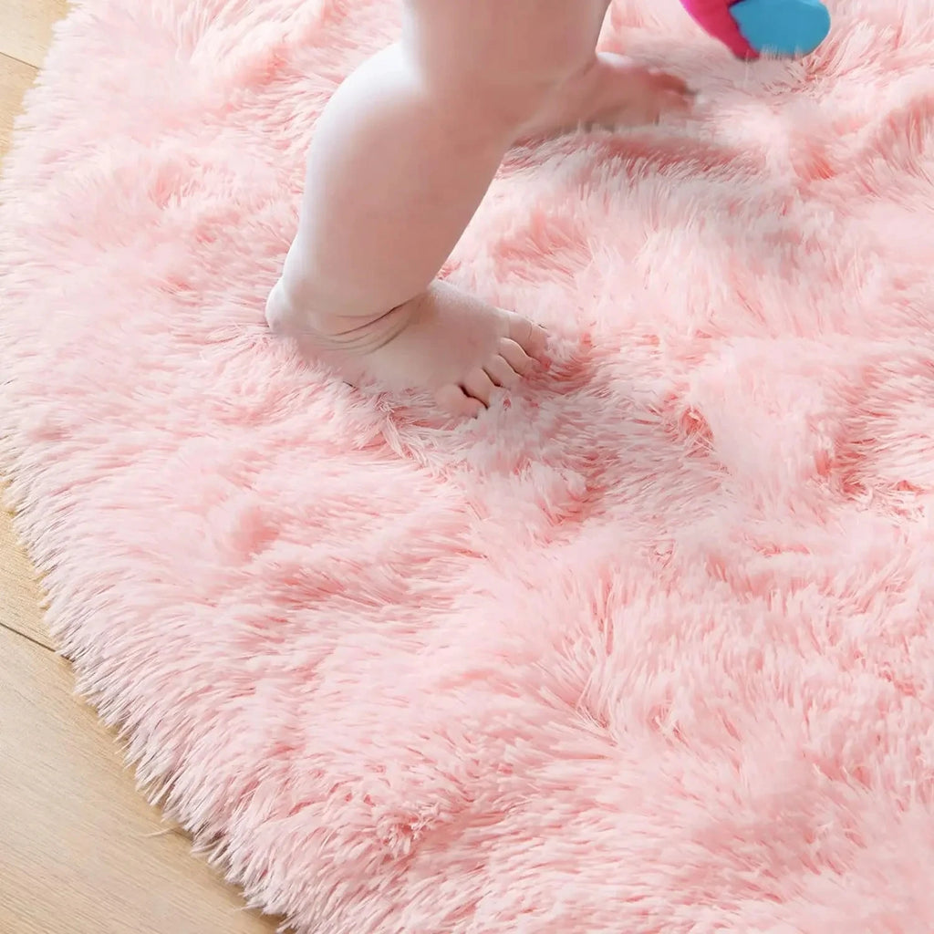 Soft pink round children's rug with a baby's feet walking on it.