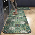 Green patterned kitchen runner mat with a mosaic tile design, placed on a wooden floor in front of a stove.