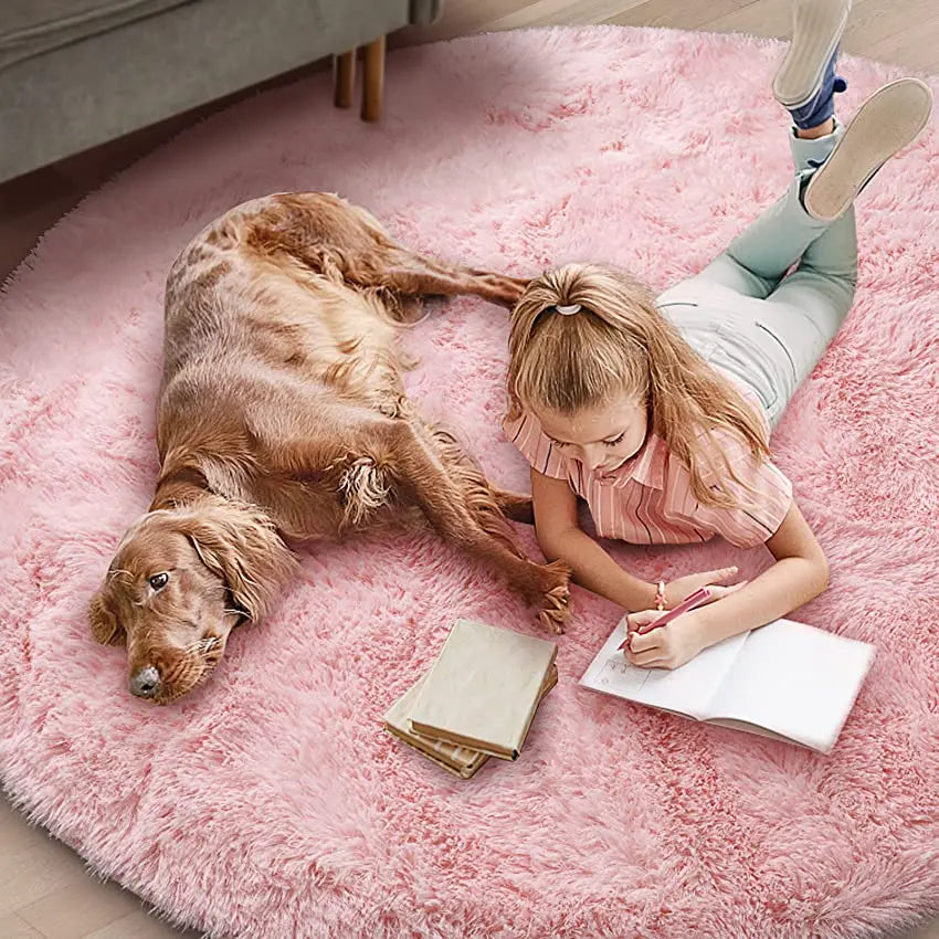 Plush pink round rug with a young girl and dog reading and drawing.