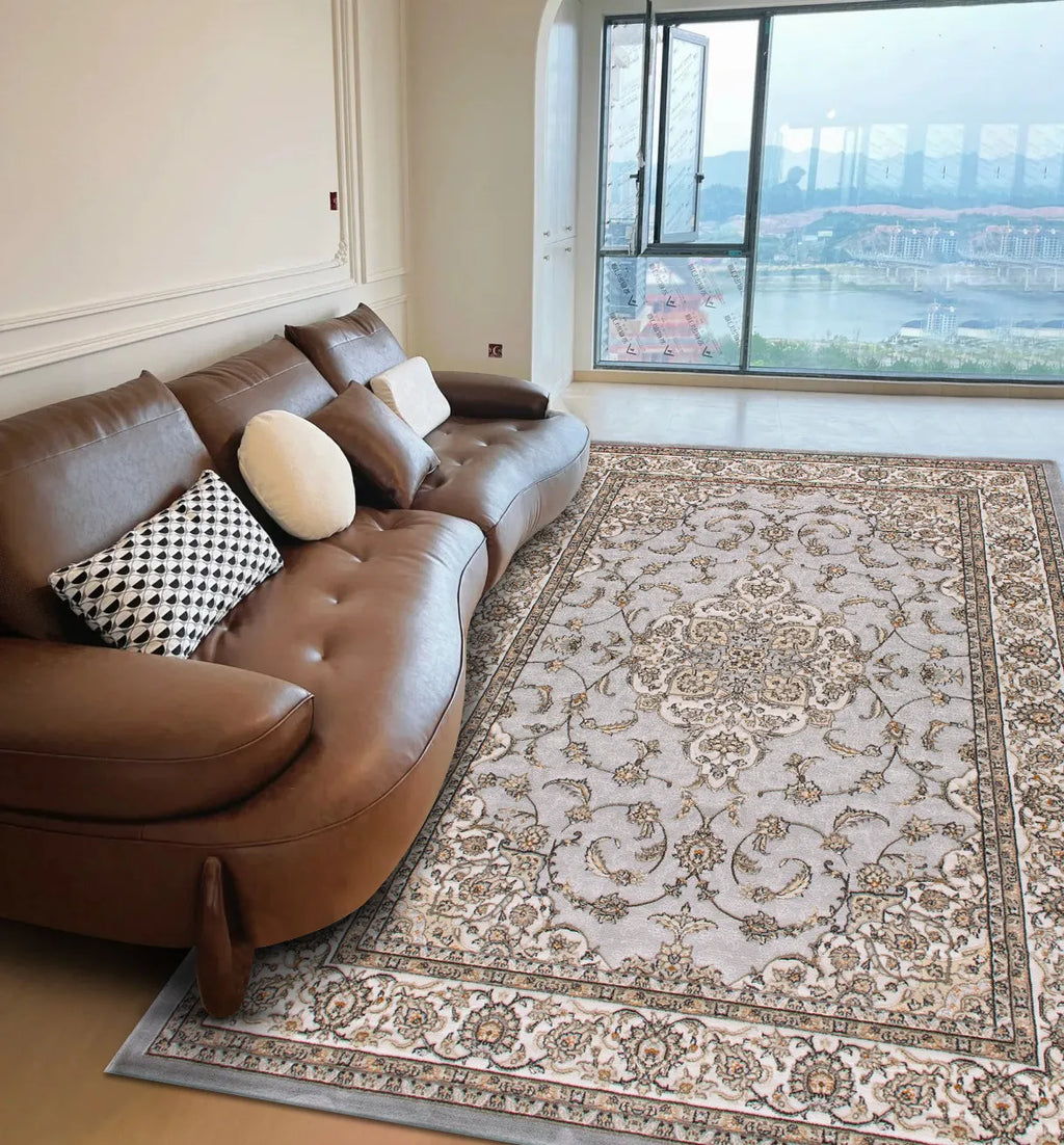 A light grey, ornate Persian style area rug with intricate floral patterns on a living room floor.