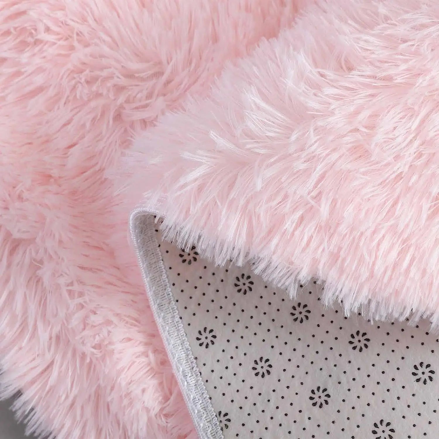 Close-up of a soft, fluffy pink round rug showing the texture and the non-slip backing.