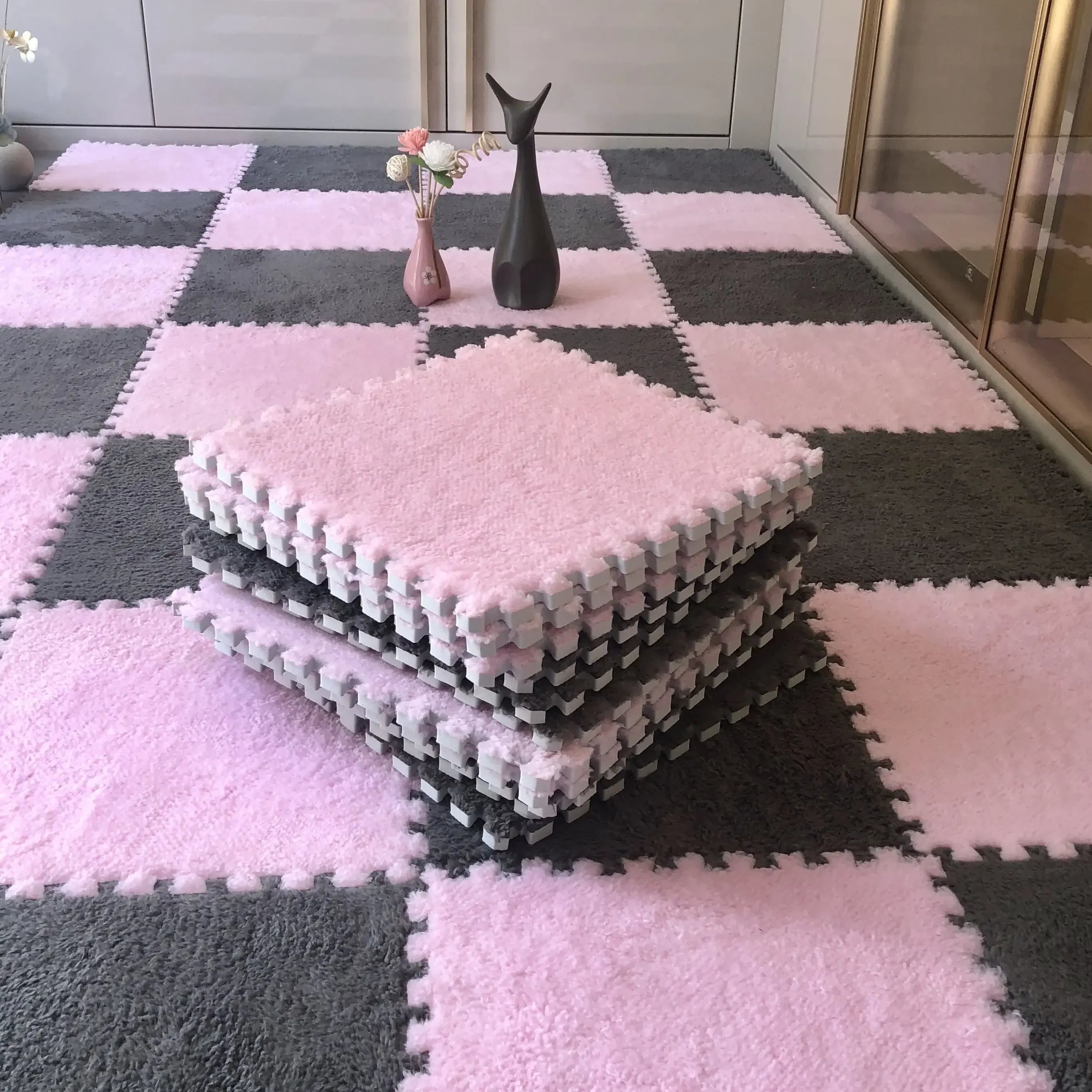 Stack of soft pink and gray interlocking foam floor tiles for kids' playrooms.