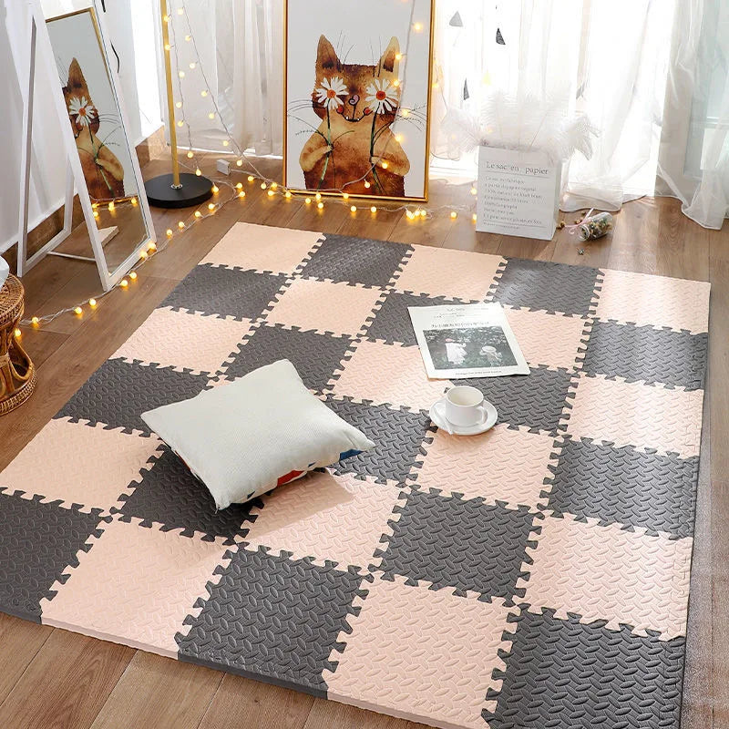 Pink and grey interlocking foam floor tiles arranged in a checkerboard pattern on a wooden floor.
