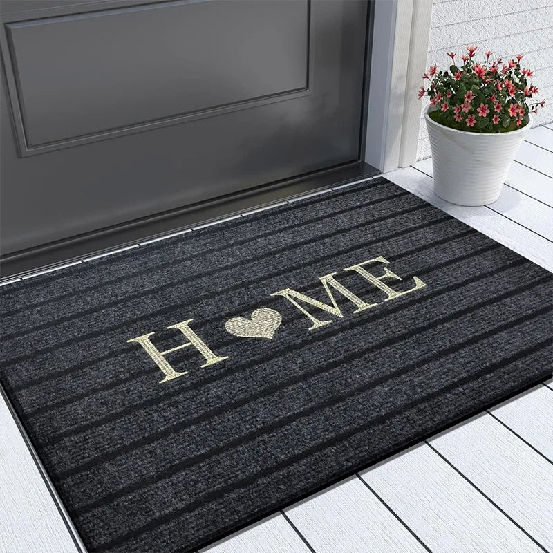Dark grey striped doormat with "HOME" and a heart design, placed on a white wooden porch.