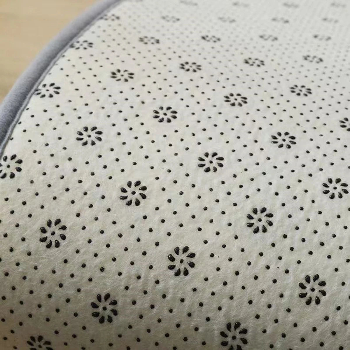Close-up view of the non-slip backing of a Tapis chambre rug, showing black dots and floral patterns.